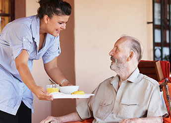 Woman Serving Food To Senior Woman Serving Food To Senior